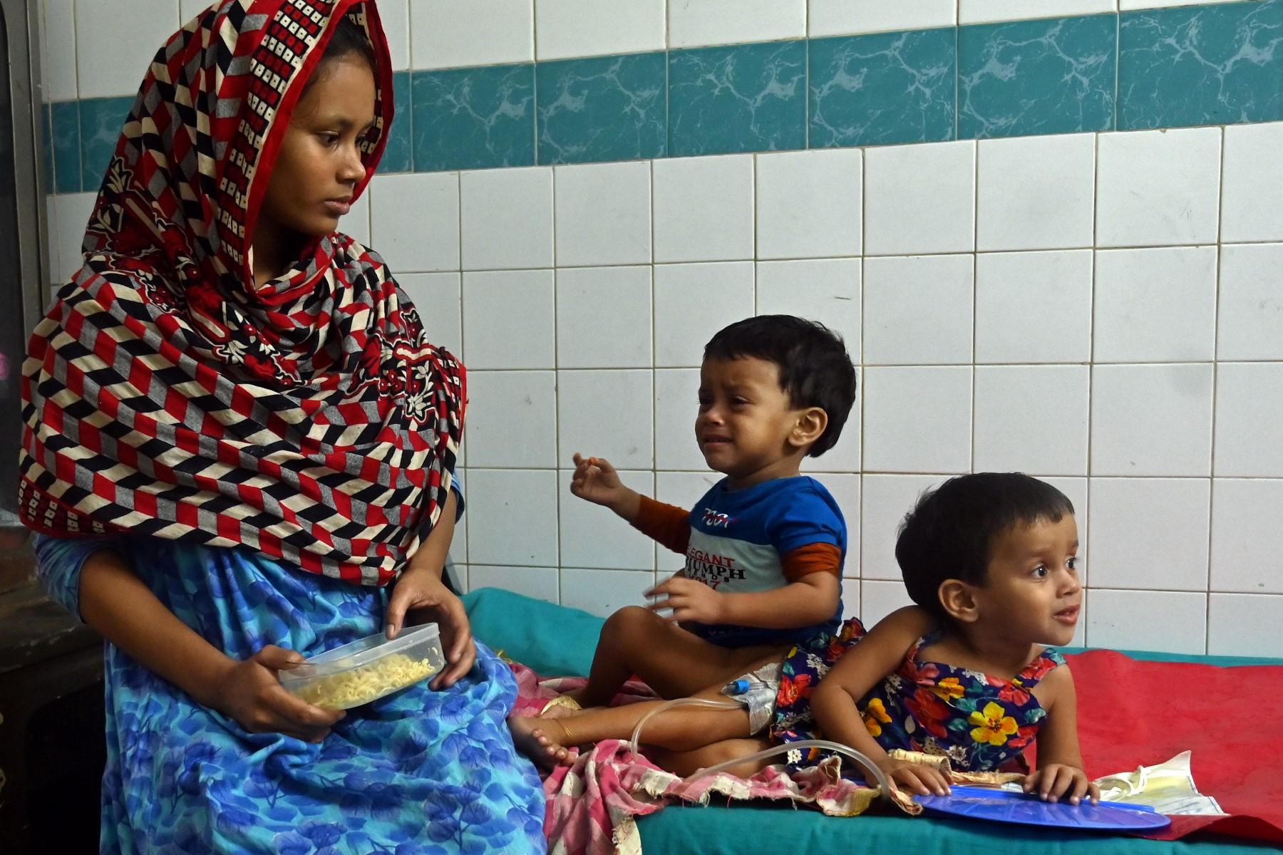 The conjoined twins Lamisa (R) and Labiba sit beside their mother Monufa on the eve of their surgery at a hospital in Dhaka on Dec 12. Photo: AFP
