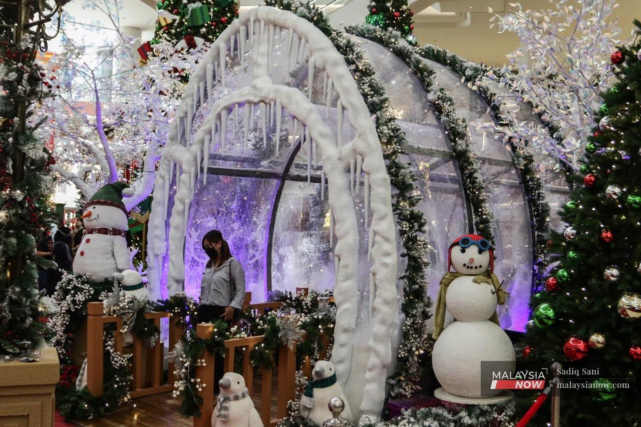 A woman poses for a picture at a replica of an ice tunnel amid other Christmas decorations at a shopping mall in Kuala Lumpur.
