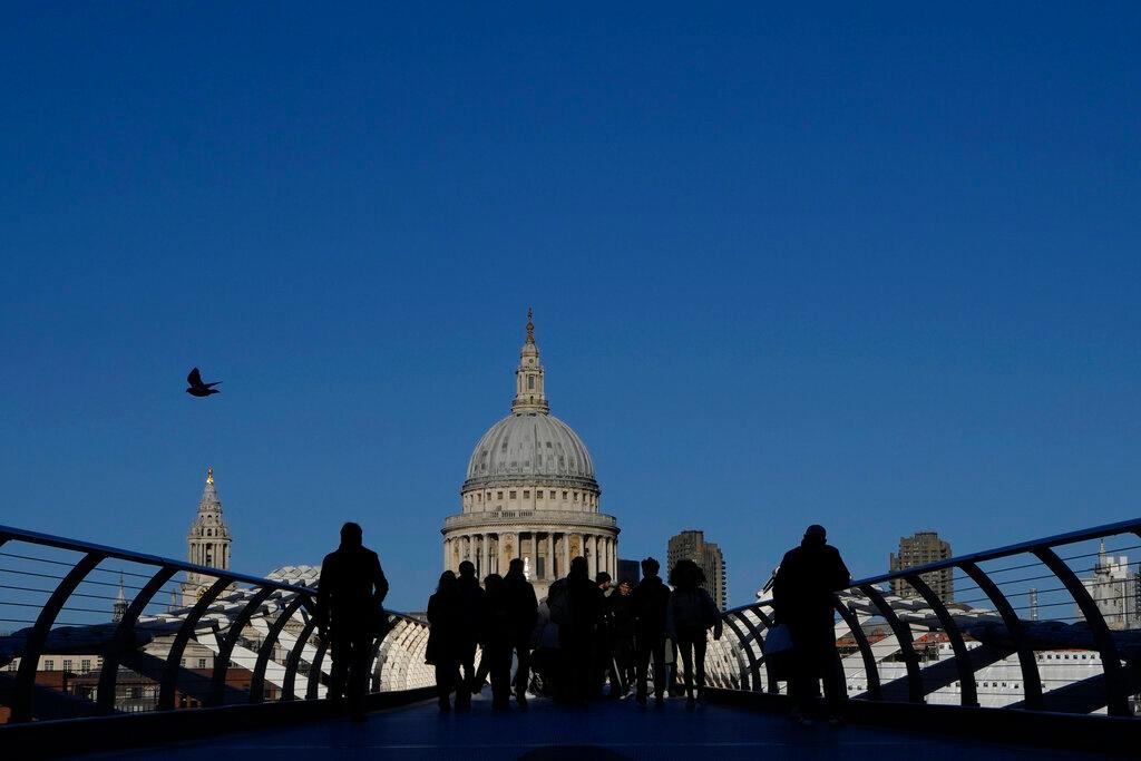 People are silhouetted as they walk over the Millennium Bridge towards St Paul's Cathedral in London, Dec 2. Photo: AP