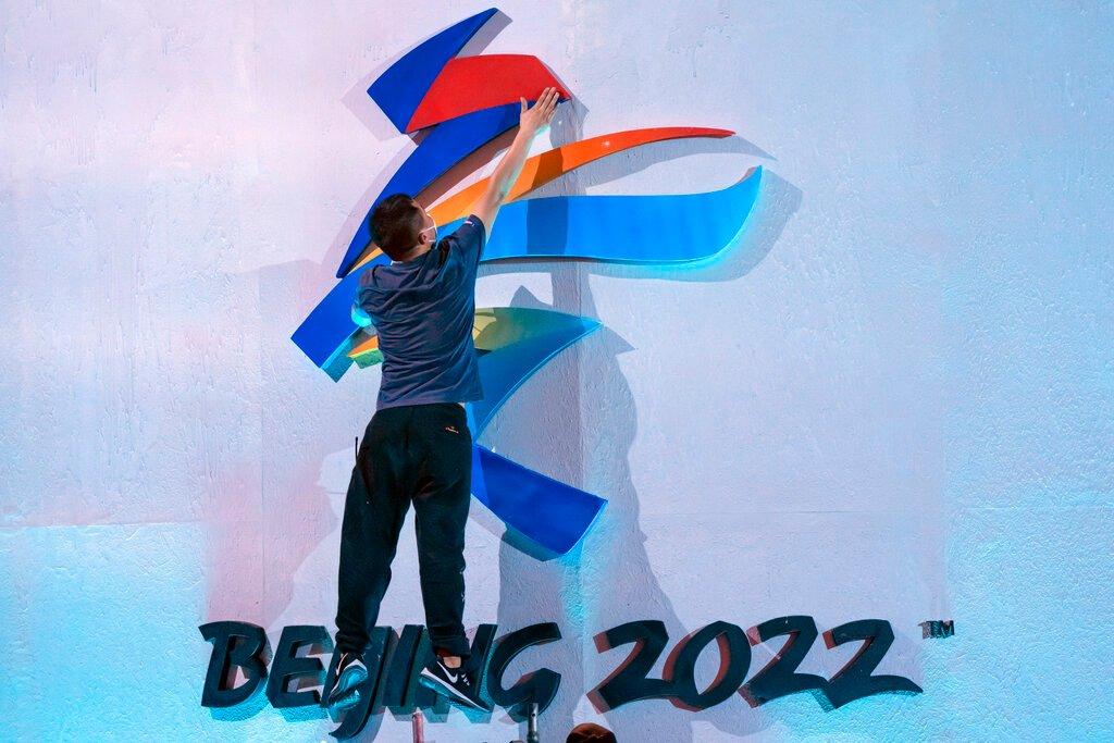 A crew member leaps to fix a logo for the 2022 Beijing Winter Olympics before a launch ceremony to reveal the motto for the Winter Olympics and Paralympics in Beijing on Sept 17. Photo: AP