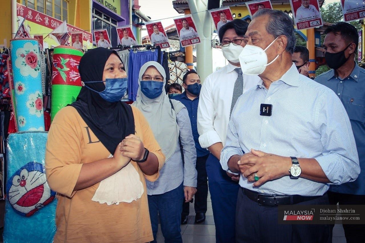 Bersatu president Muhyiddin Yassin speaks with a trader during a walkabout in Lebuh India, Kuching.