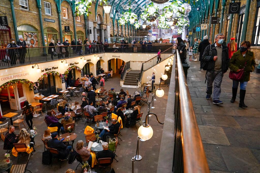 People sit at outside tables in Covent Garden Market, in London, Dec 16. Photo: AP