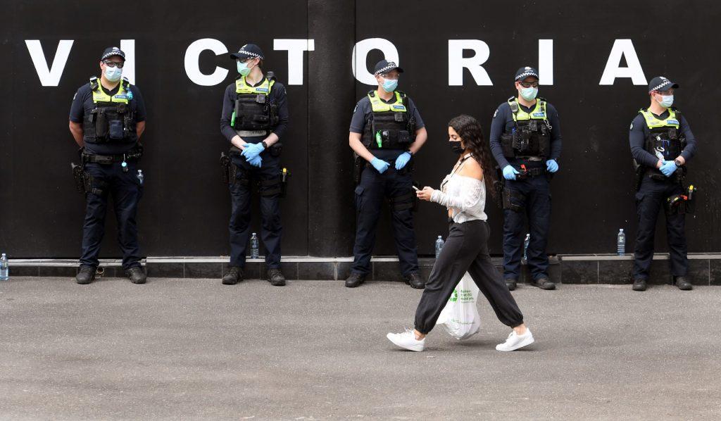 A woman carries her shopping while police officers stand guard on a Melbourne street on Sept 29. Health officials blamed gatherings at pubs and clubs for the 'rapid rise' in cases. Photo: AFP