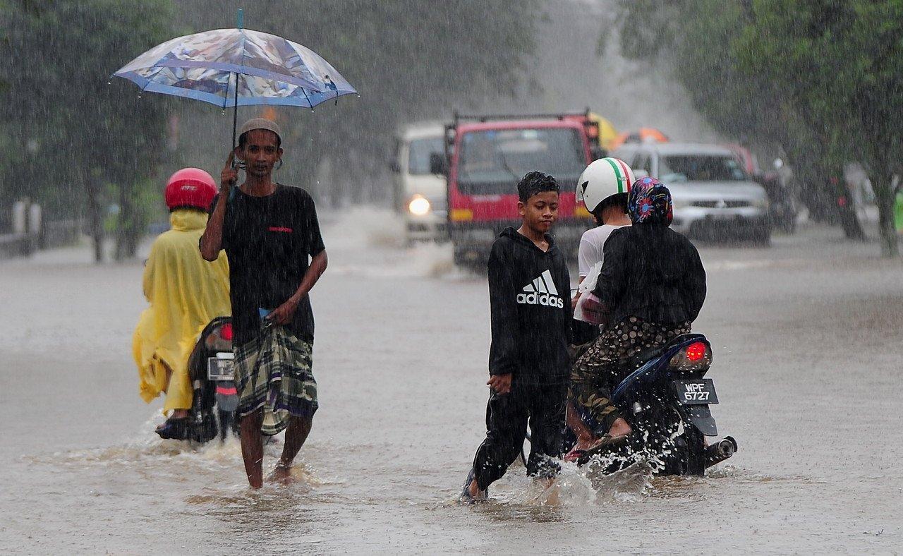 Pedestrians and motorists make their way through heavy rain in Kampung Jalan Kebun Seksyen 30 in Shah Alam. Photo: Bernama