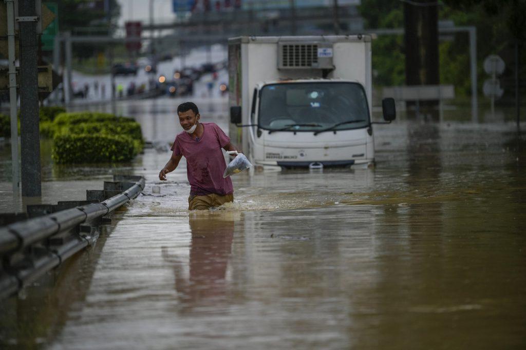 Seorang pemandu lori meninggalkan kenderaannya yang ditenggelami banjir akibat limpahan Sungai Damansara di Batu Tiga, Shah Alam. Gambar: Bernama