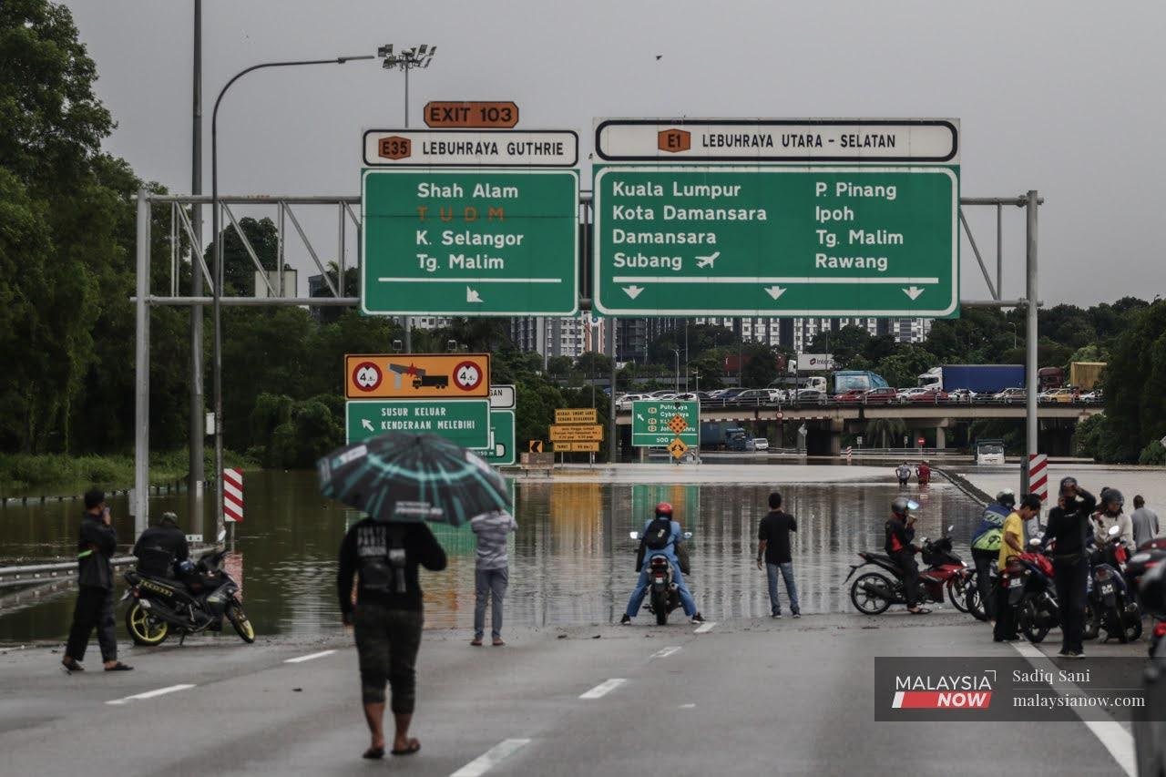 Motorists wait for water levels to subside following the heavy rain which left several lanes along the New Klang Valley Expressway flooded since early this morning.