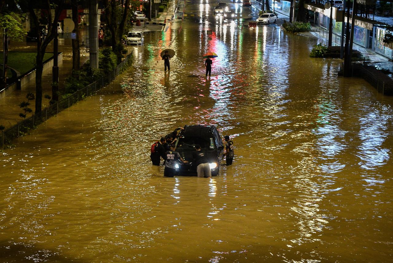 A group of men try to push a car stranded in flood waters in Kuala Lumpur last night. Photo: Bernama
