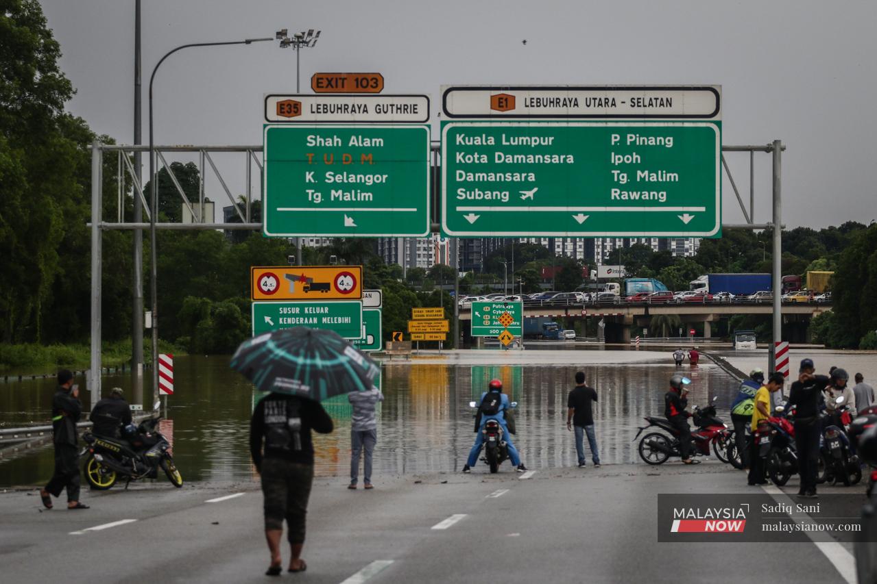 Motorists wait for flood waters to subside before attempting to continue their journeys at the North Klang Valley Expressway.