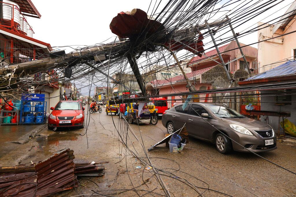 Cars pass by a toppled electrical post due to Typhoon Rai in Surigao city, Surigao del Norte, southern Philippines as power supply remains down on Dec 19. Photo: AP