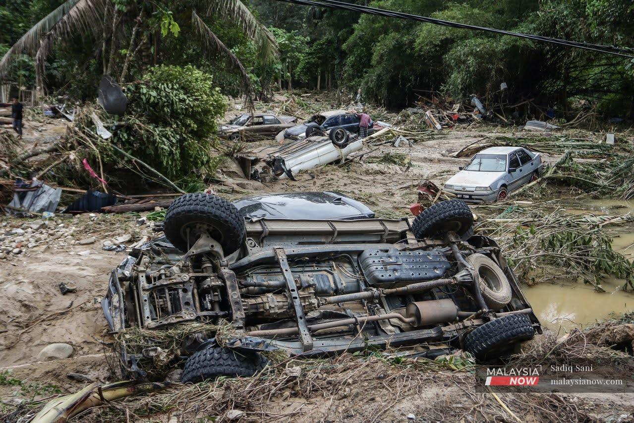 A villager checks a car, one among many vehicles that were upended and washed away by the flood that hit Kampung Jawa in Hulu Langat.