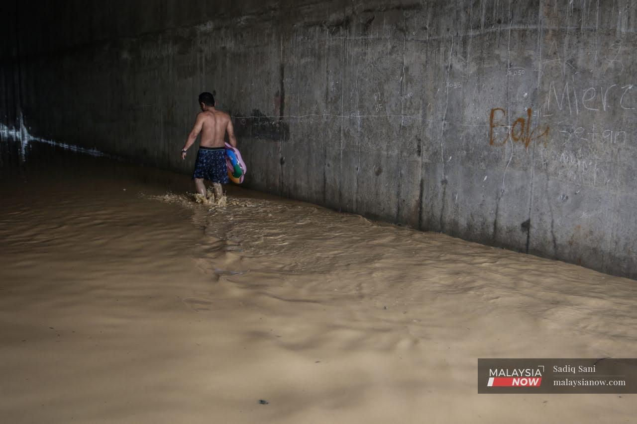 Seorang lelaki meredah kawasan banjir di Kampung Sungai Balak.
