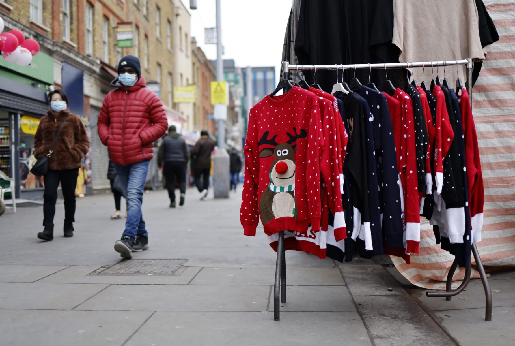 Pedestrians wearing face coverings to help mitigate the spread of Covid-19, walk past a Christmas jumpers displayed for sale on a market stall in east London on Dec 20. Photo: AFP