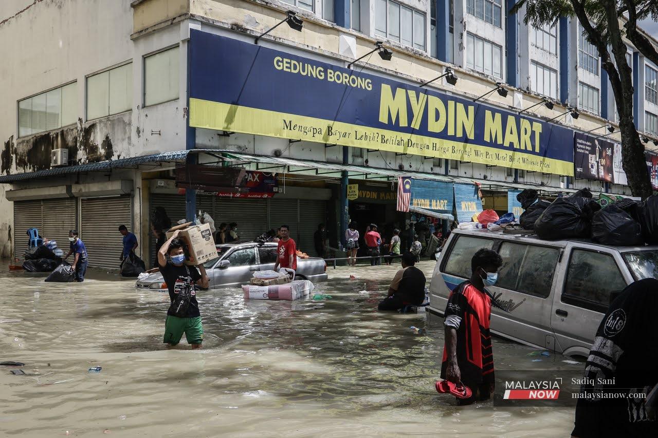 Residents carry goods away from the Mydin Mart in Taman Sri Muda, Shah Alam.