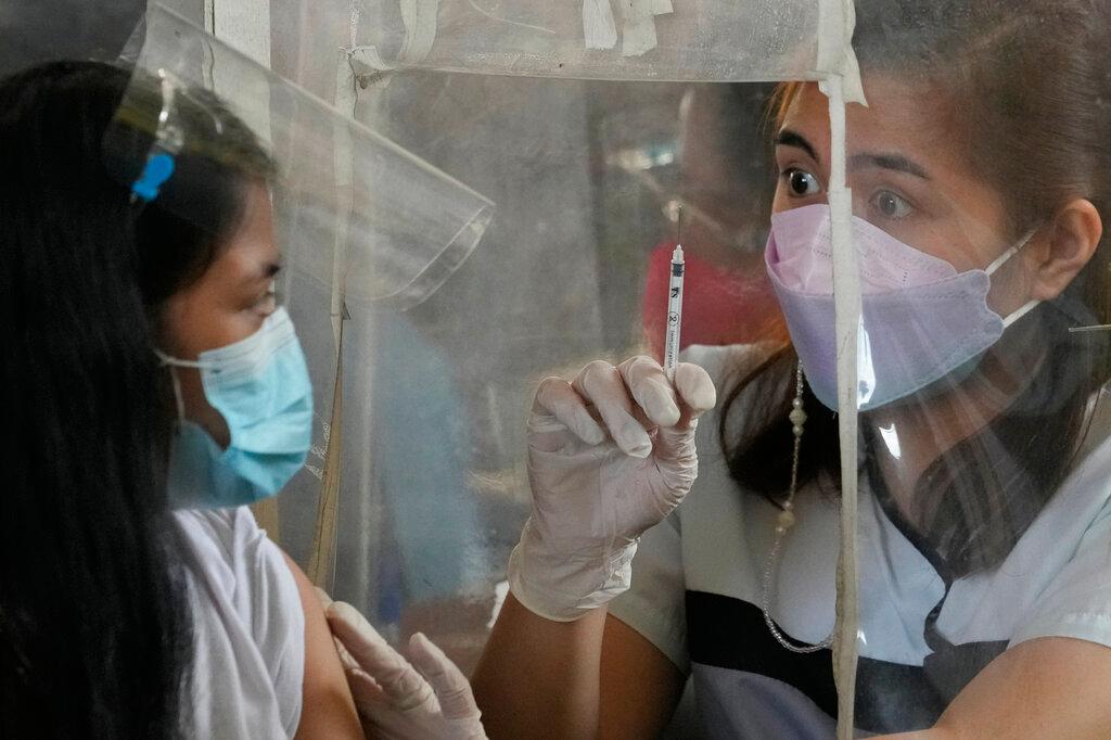 A health worker shows an empty syringe after inoculating a woman with AstraZeneca's Covid-19 vaccine at a school in Quezon city, Philippines, Nov 29. Photo: AP
