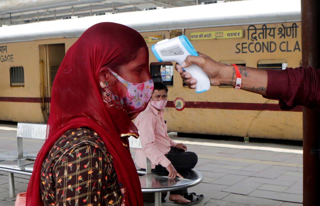 A health worker checks the body temperature of a passenger arriving at a railway station as a precaution against Covid-19 before allowing her to enter the city, in Mumbai, India, Dec 7. Photo: AP