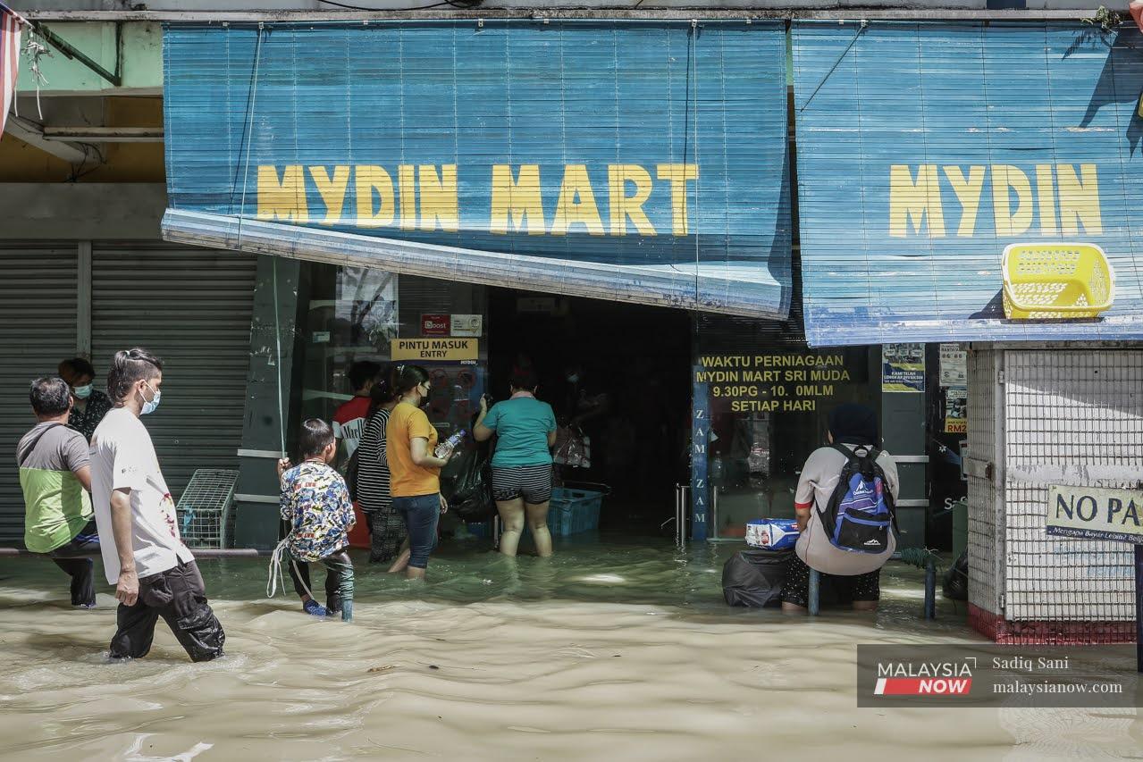 Flood victims wade through the water towards the Mydin Mart branch in Taman Sri Muda, Shah Alam.