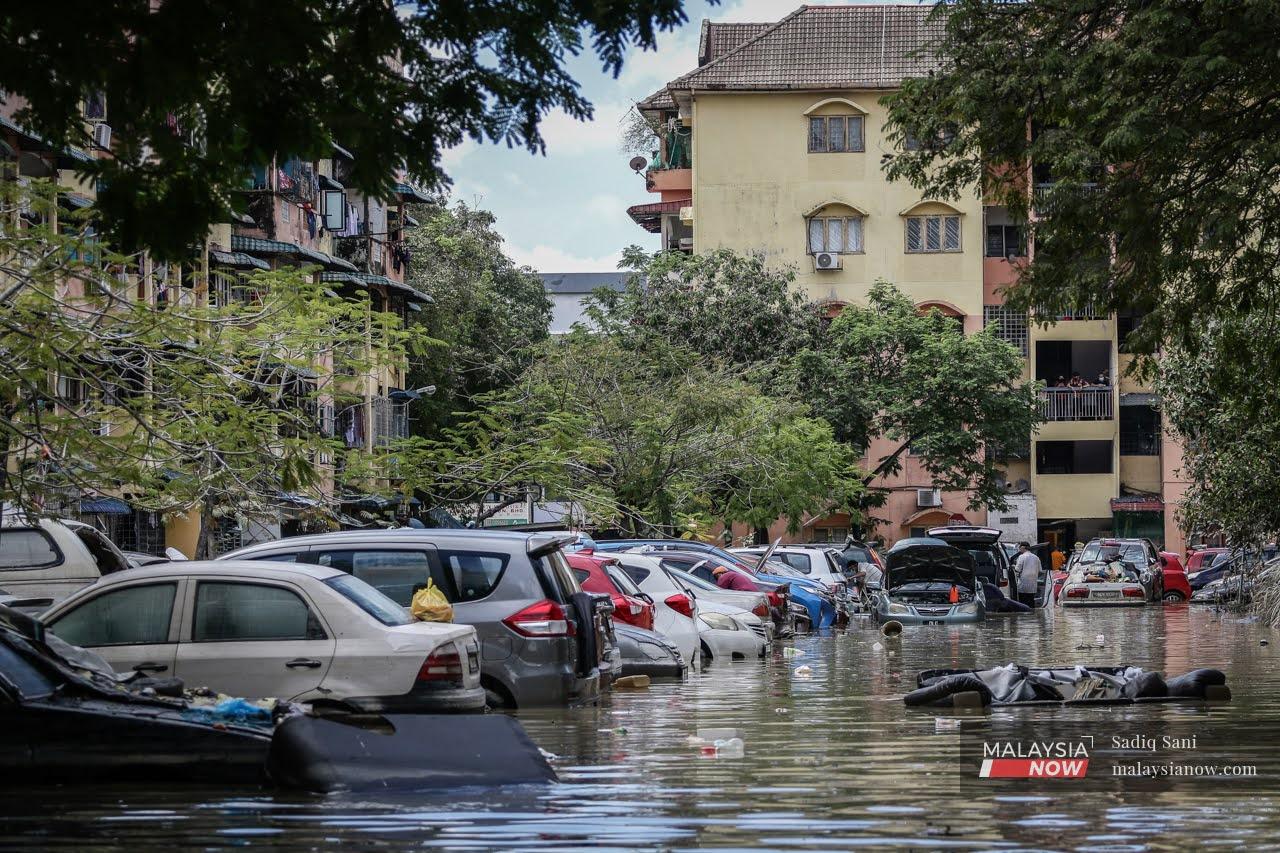 Garbage floats in the floodwater as residents check their vehicles in Taman Sri Muda, Shah Alam, one of the worst-hit areas in Selangor.