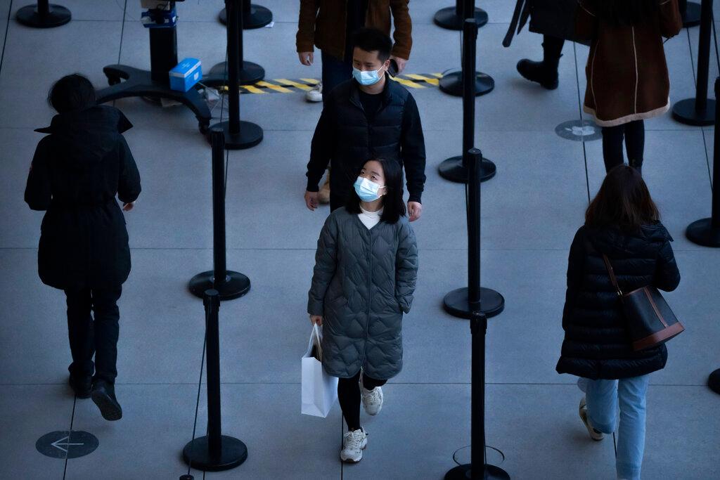 People wearing face masks to protect against Covid-19 wait in line to enter a store at an outdoor shopping centre in Beijing, Nov 13. Photo: AP