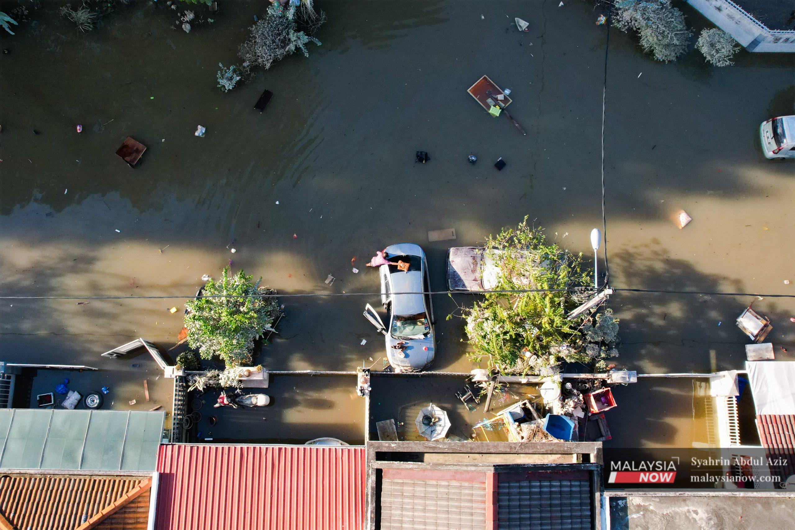 Seorang mangsa banjir sedang membersihkan keretanya di Taman Sri Muda. Selangor menjadi negeri yang paling teruk terjejas akibat banjir selepas hujan berterusan hujung minggu lalu.