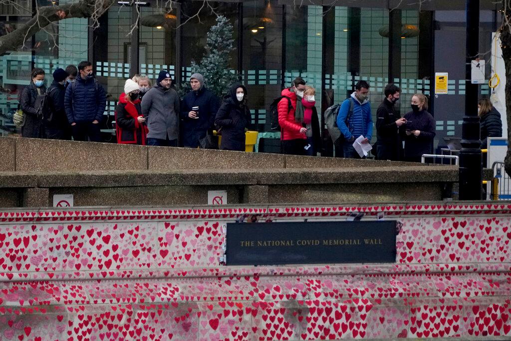 People queue for coronavirus booster jabs at St Thomas' Hospital, with the National Covid Memorial Wall in the foreground, in London, Dec 14. Photo: AP