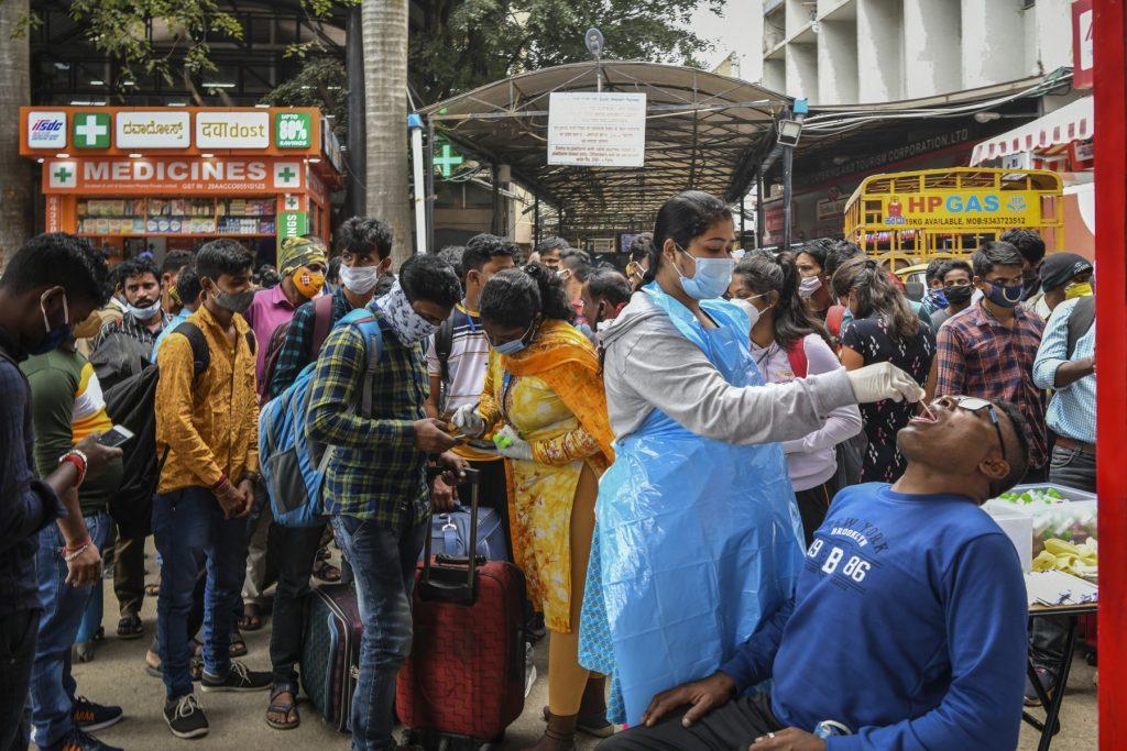 A health official screens a passenger for Covid-19 at a railway station during an enforcement drive in Bangalore on Dec 3. Photo: AFP