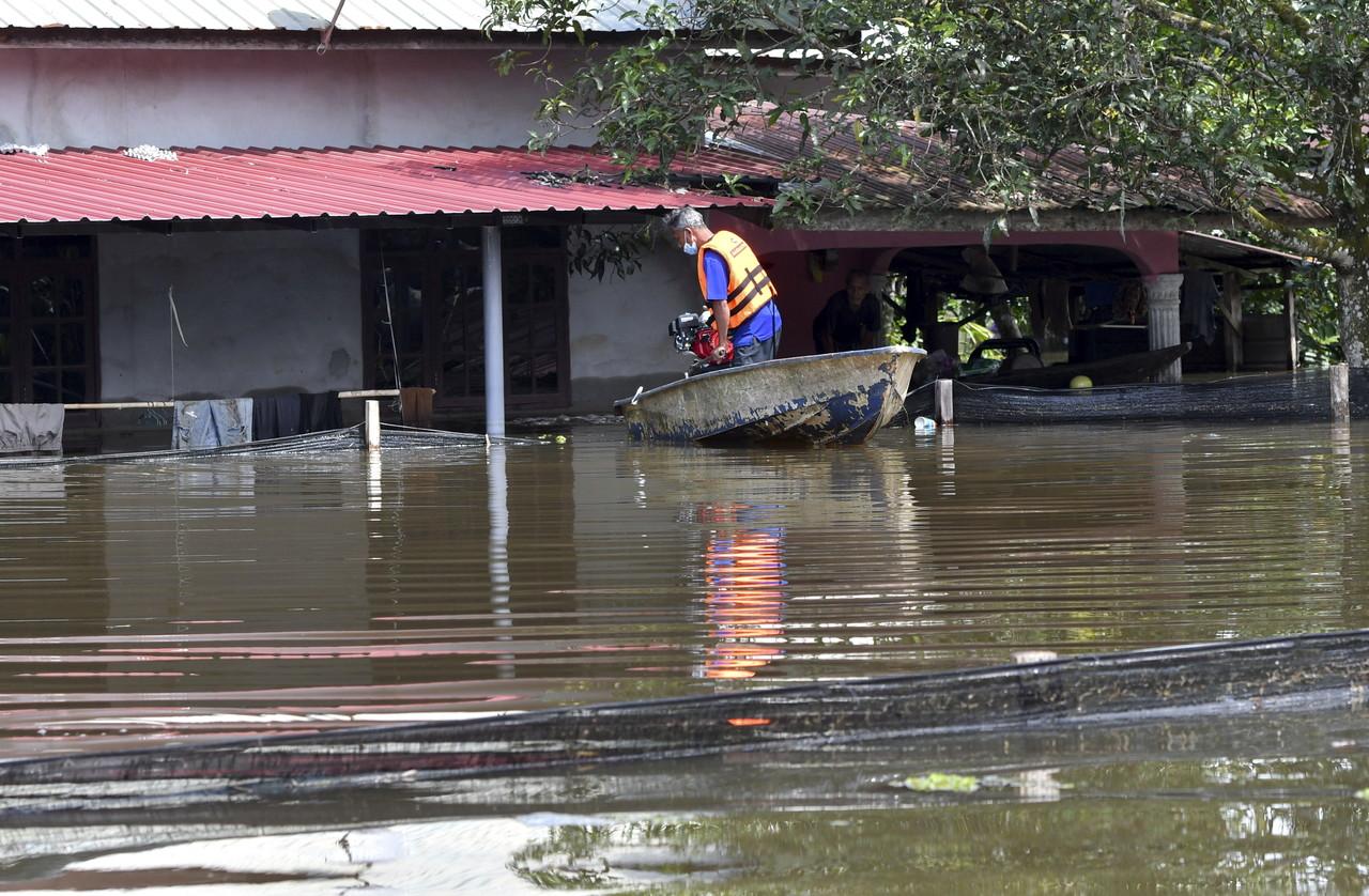 A man checks on his house which was partially submerged in the floods which hit Kampung Padang Licin in Pasir Mas. Photo: Bernama