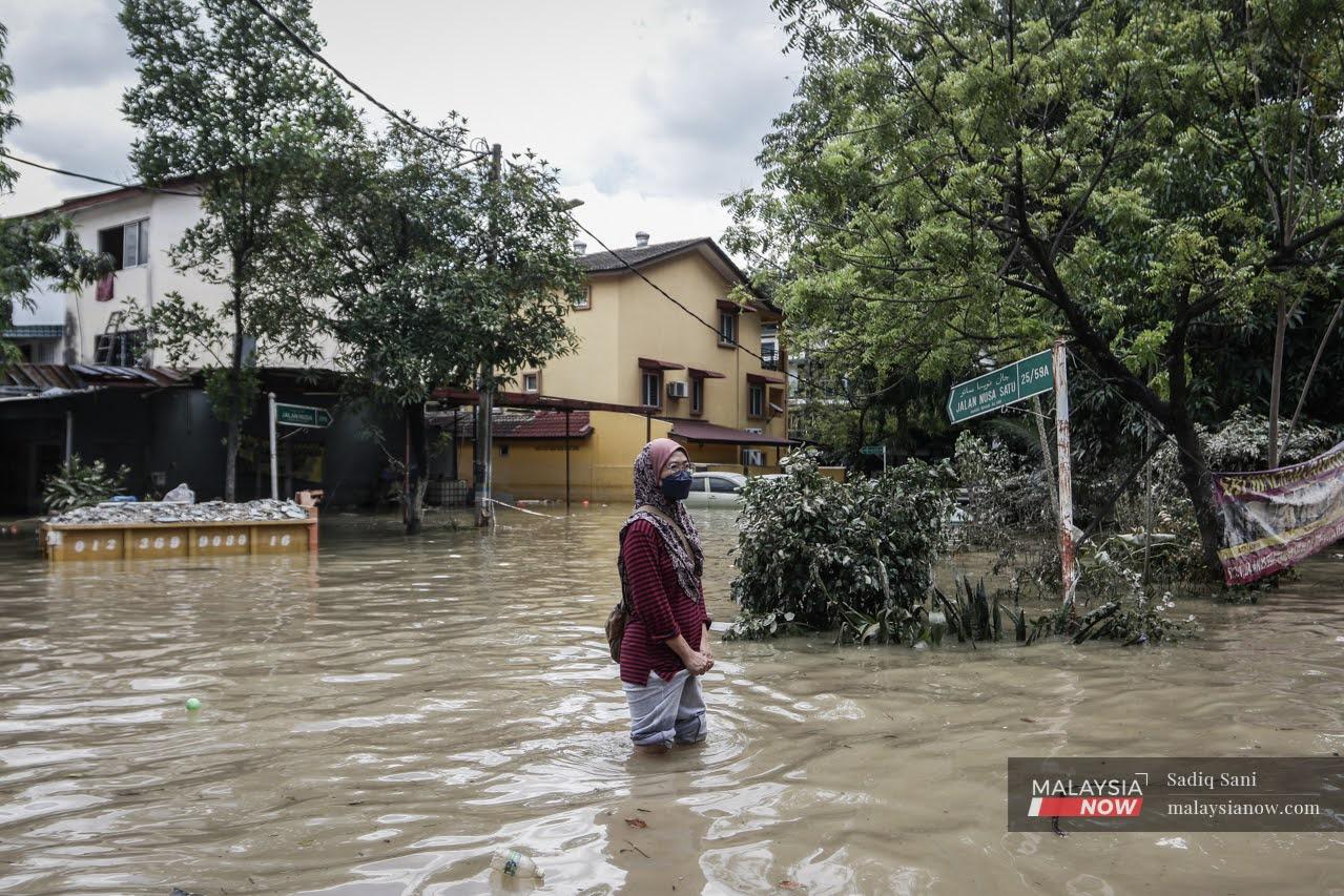 A woman wades through the floodwaters in Taman Sri Muda, Shah Alam.