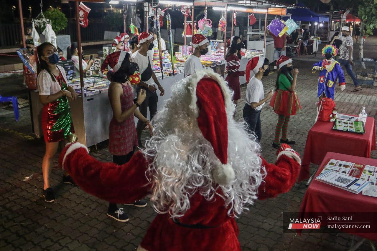 Children present Christmas songs at an open-air carolling session while Santa Claus conducts, at the Melaka Portuguese settlement in Ujong Pasir.