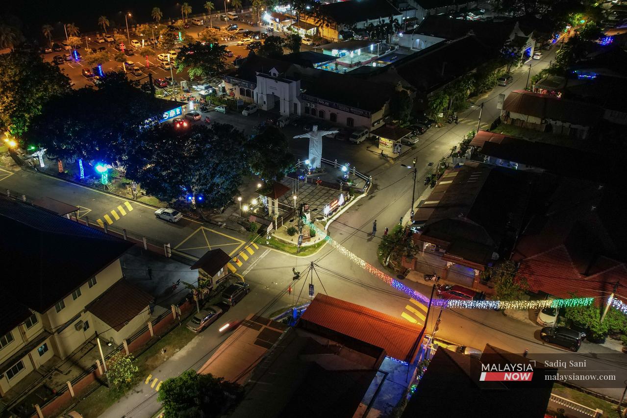 Colourful Christmas lights hang across a road in the Melaka Portuguese settlement in Ujong Pasir, casting a glow on a statue of Christ the Redeemer.