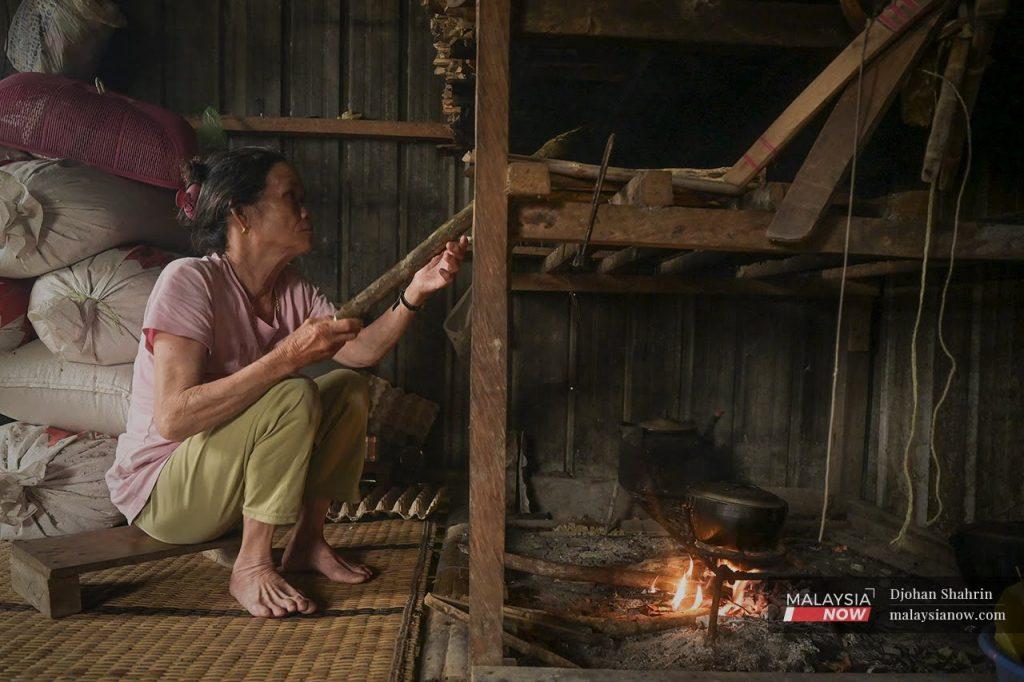 Didun Sikau memasak nasi menggunakan dapur kayu di rumahnya di Kampung Sapit, Sarawak.