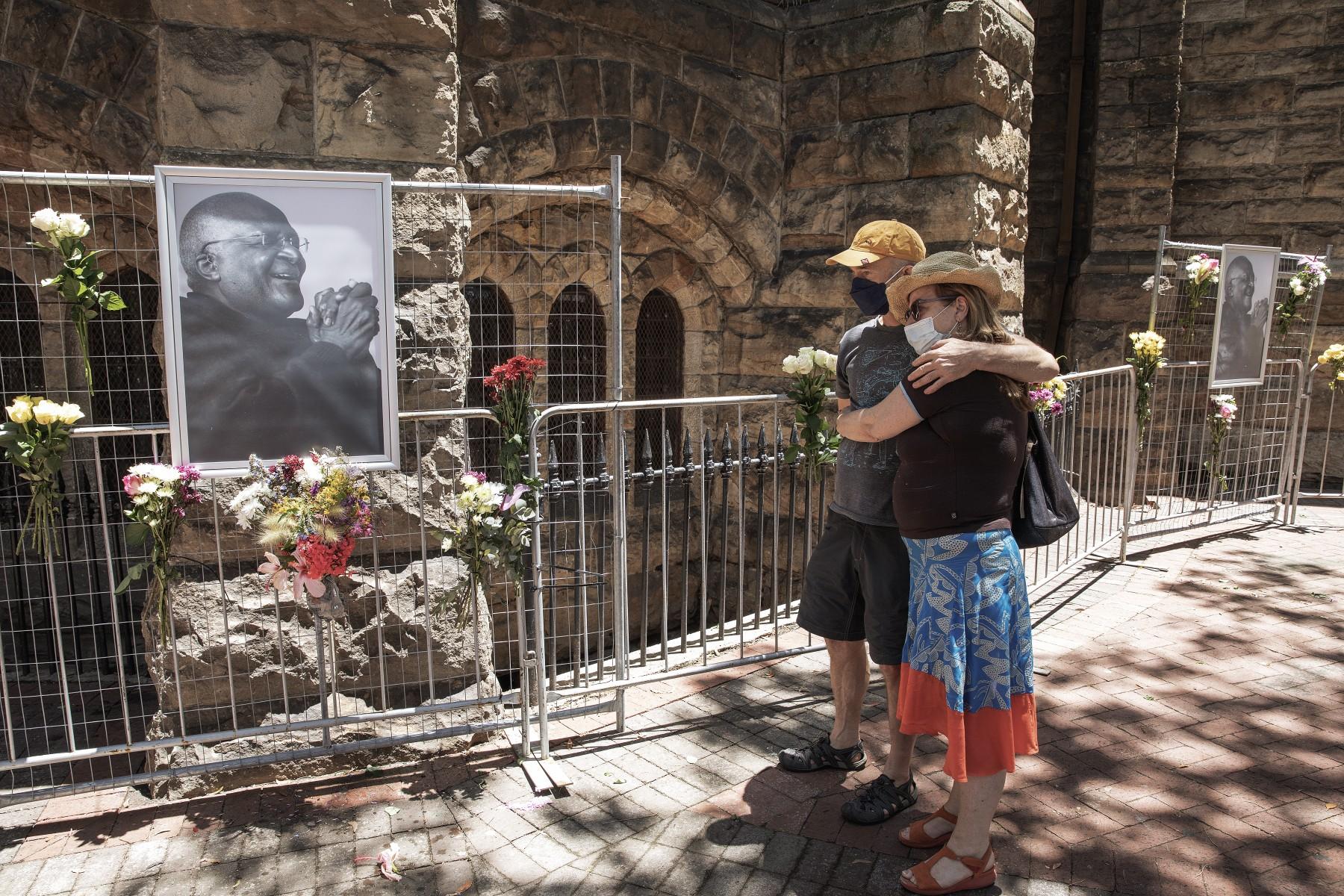 A couple stands by a picture of the late South African Archbishop Desmond Tutu in the wake of his death outside St George's Cathedral in Cape Town on Dec 26. Photo: AFP