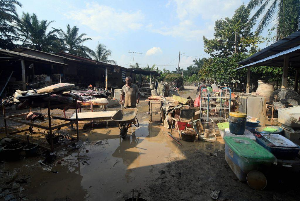 Mangsa banjir di Kampung Labohan Dagang Kuala Langat di Banting membersihkan barangan rumah yang terkena lumpur. Gambar: Bernama