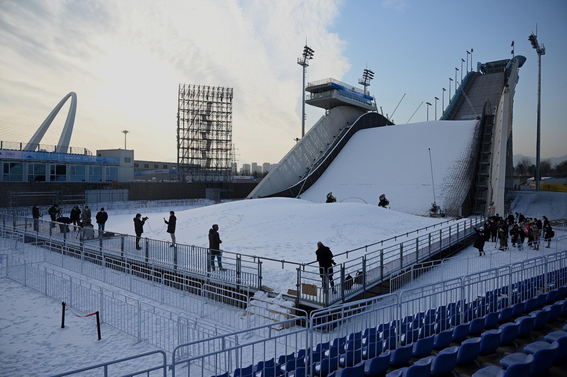 Journalists work in front of the Shougang Big Air venue, which will host the big air freestyle skiing and snowboarding competitions at the Beijing 2022 Winter Olympics, at the Shougang Park in Beijing on Dec 15. Photo: AFP