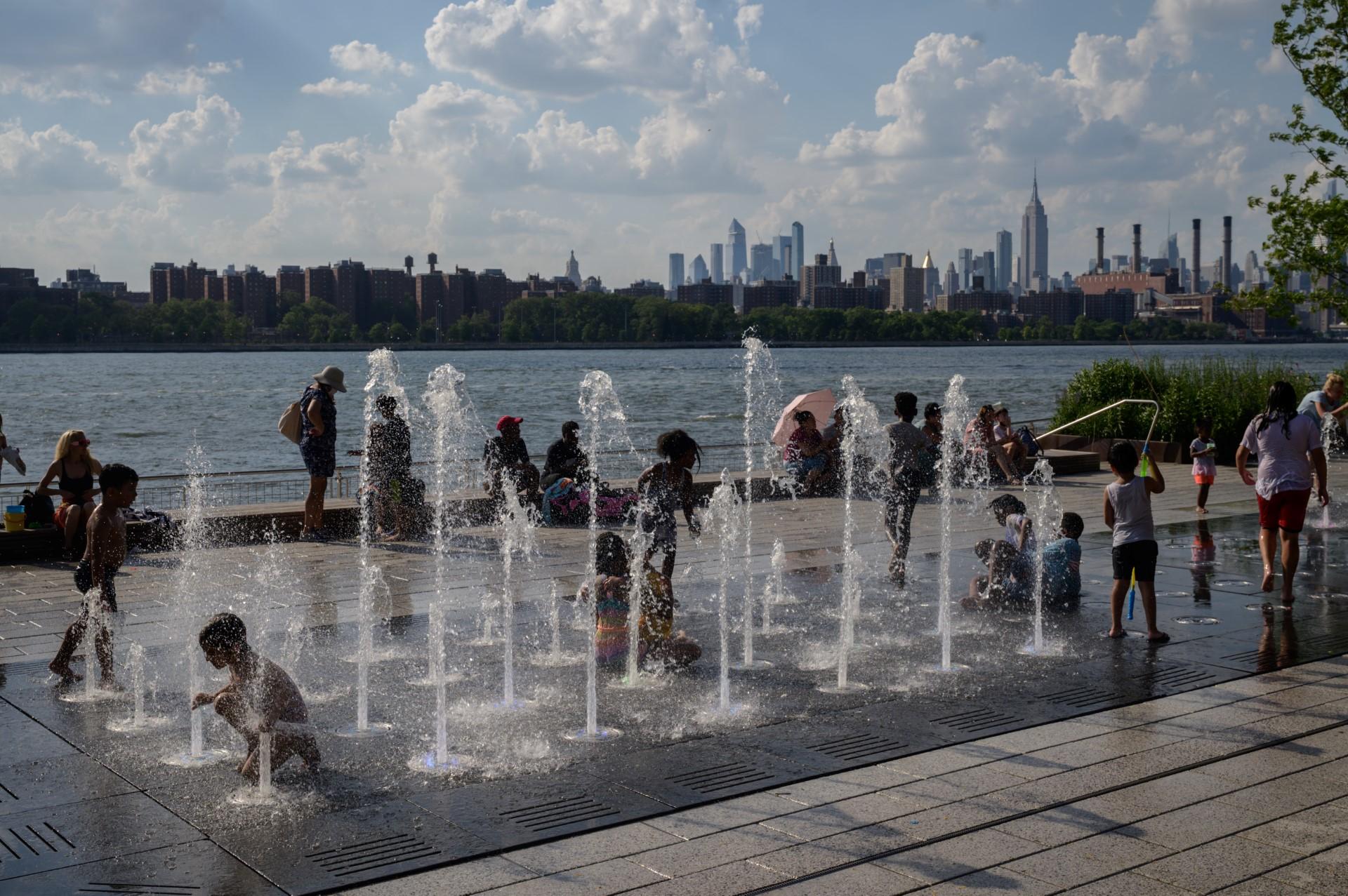 Children play in a water fountain before the Manhattan city skyline at a park in Brooklyn, New York, on June 30. Photo: AFP