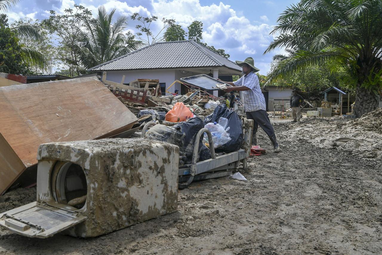 A homestay owner in Dengkil throws out furniture and other items damaged by the floods. Photo: Bernama