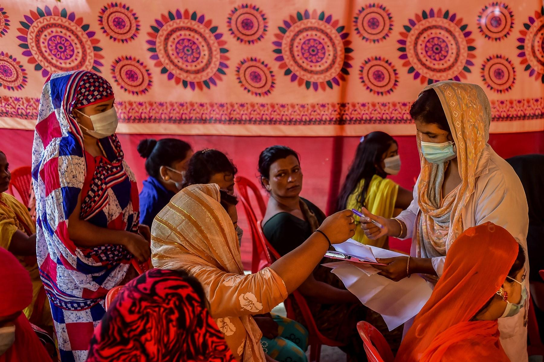 A health official registers the details of women who gathered to get themselves inoculated with the Sinopharm vaccine against Covid-19 at special vaccination drive held in Daulatdia on Aug 18. Photo: AFP