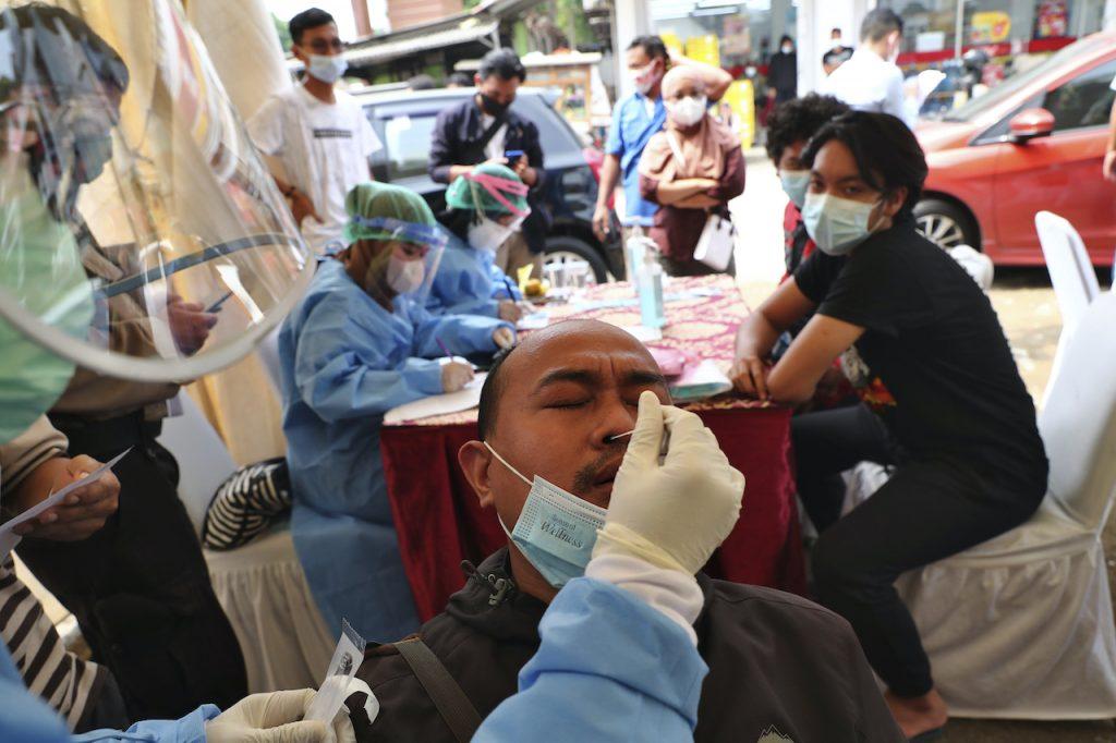 Seorang lelaki menjalani ujian swab Covid-19 ketika sampai di Tangerang dari Jakarta. Gambar: AP