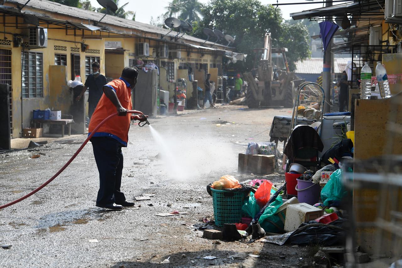 A worker from the Solid Waste Management and Public Cleansing or SWCorp sprays water at a housing area as part of clean-up efforts in Kampung RTB Rancangan Tanah Belia Bukit Changgang Sepang. Photo: Bernama