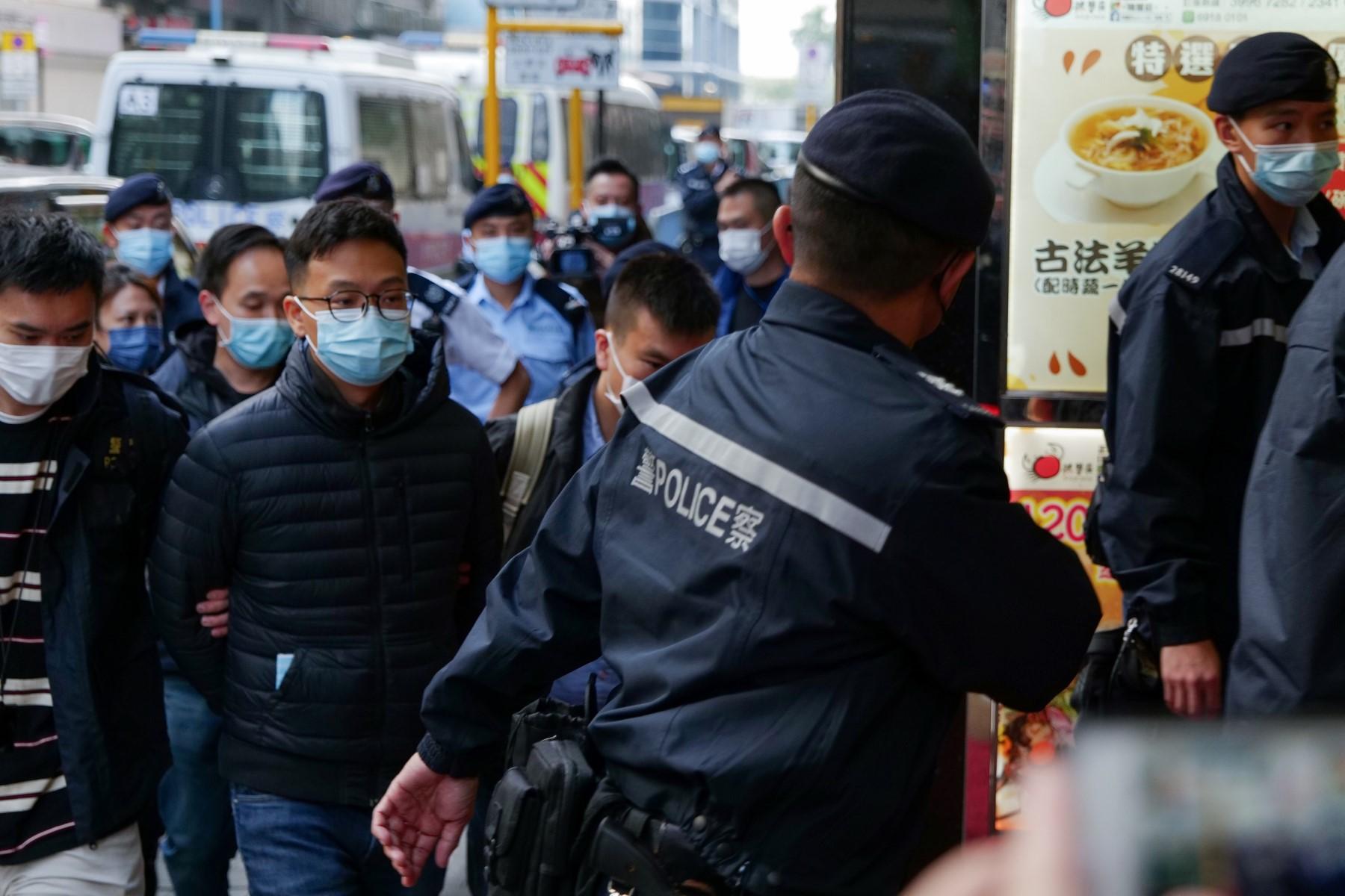 Stand News chief editor Patrick Lam (second left, foreground) is brought to the news outlet's office building in handcuffs after police were deployed to search the premises in Hong Kong's Kwun Tong district on Dec 29. Photo: AFP