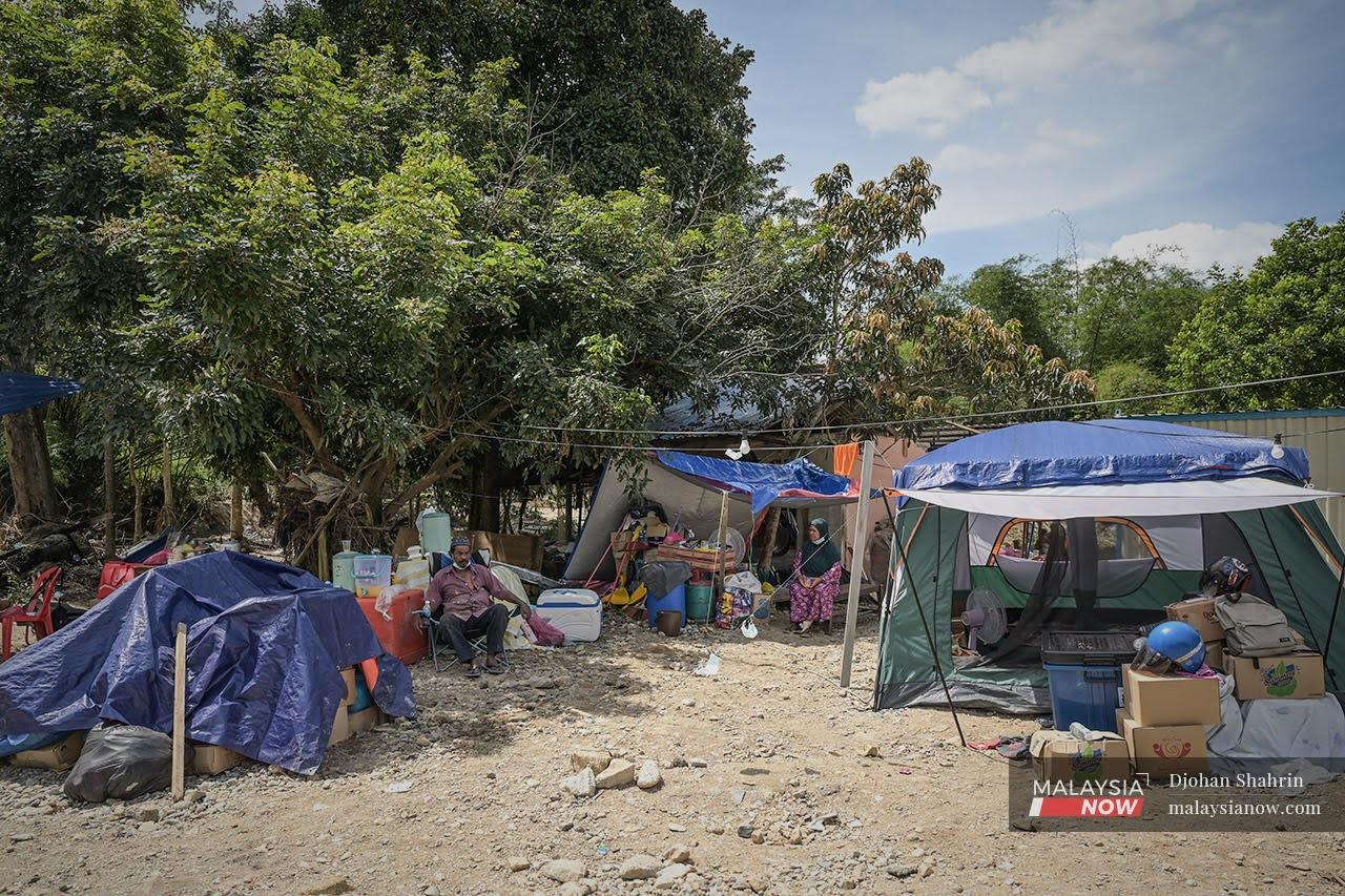 Flood victims sit in tents outside their home which was damaged by the recent floods in Jalan Sungai Lui in Hulu Langat.