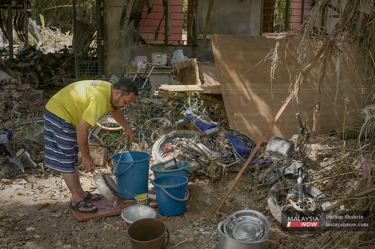 A man goes through what remains of his belongings after the flood that hit Jalan Sungai Lui in Hulu Langat, Selangor.