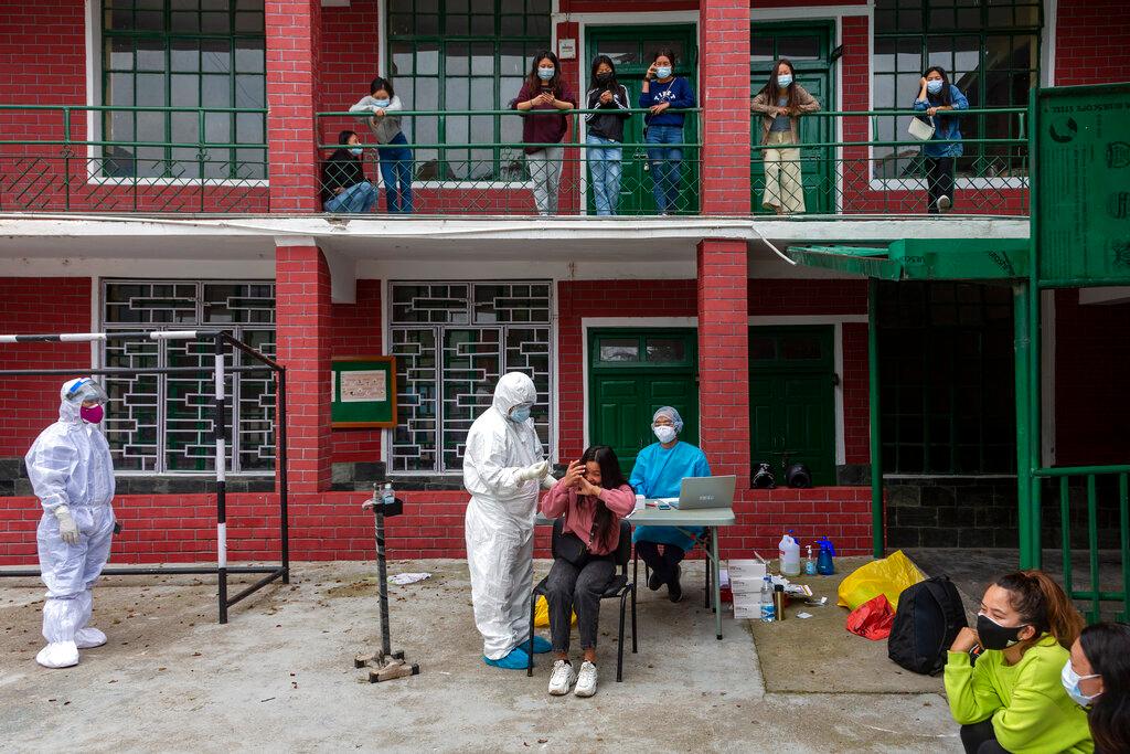 A woman reacts to her swab probe as a medical staff from the Tibetan Delek Hospital takes her sample to test for Covid-19 in the compound of a school in Dharmsala, India, May 19. Photo: AP