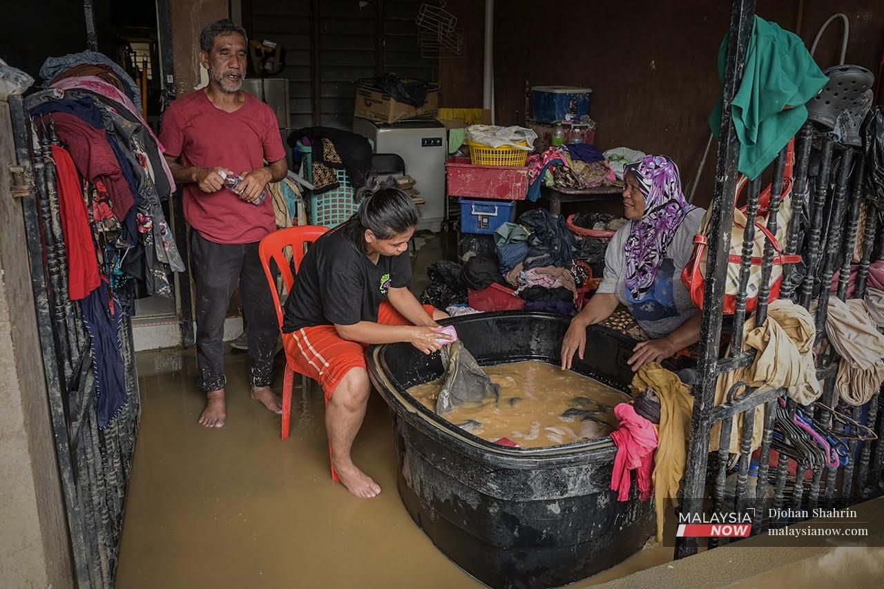 Residents in Taman Sri Nanding in Hulu Langat rinse their clothes in a large bucket to clean off the mud that collected after the massive floods last week.