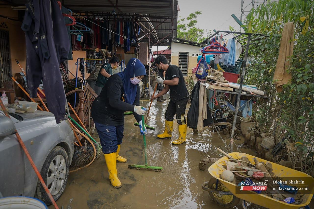 Beberapa sukarelawan dari Ipoh membantu penduduk Taman Sri Nanding membersihkan lumpur akibat kesan banjir yang melanda Hulu Langat.
