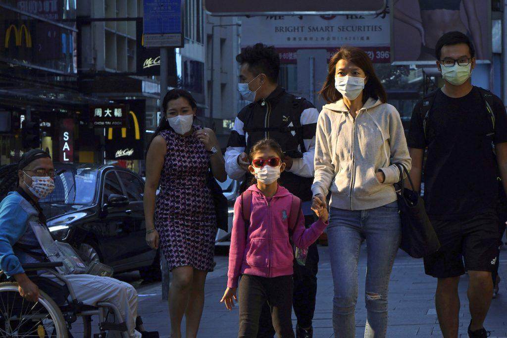 People wearing face masks to protect against Covid-19 walk along a street in Hong Kong, Nov 30. Photo: AP