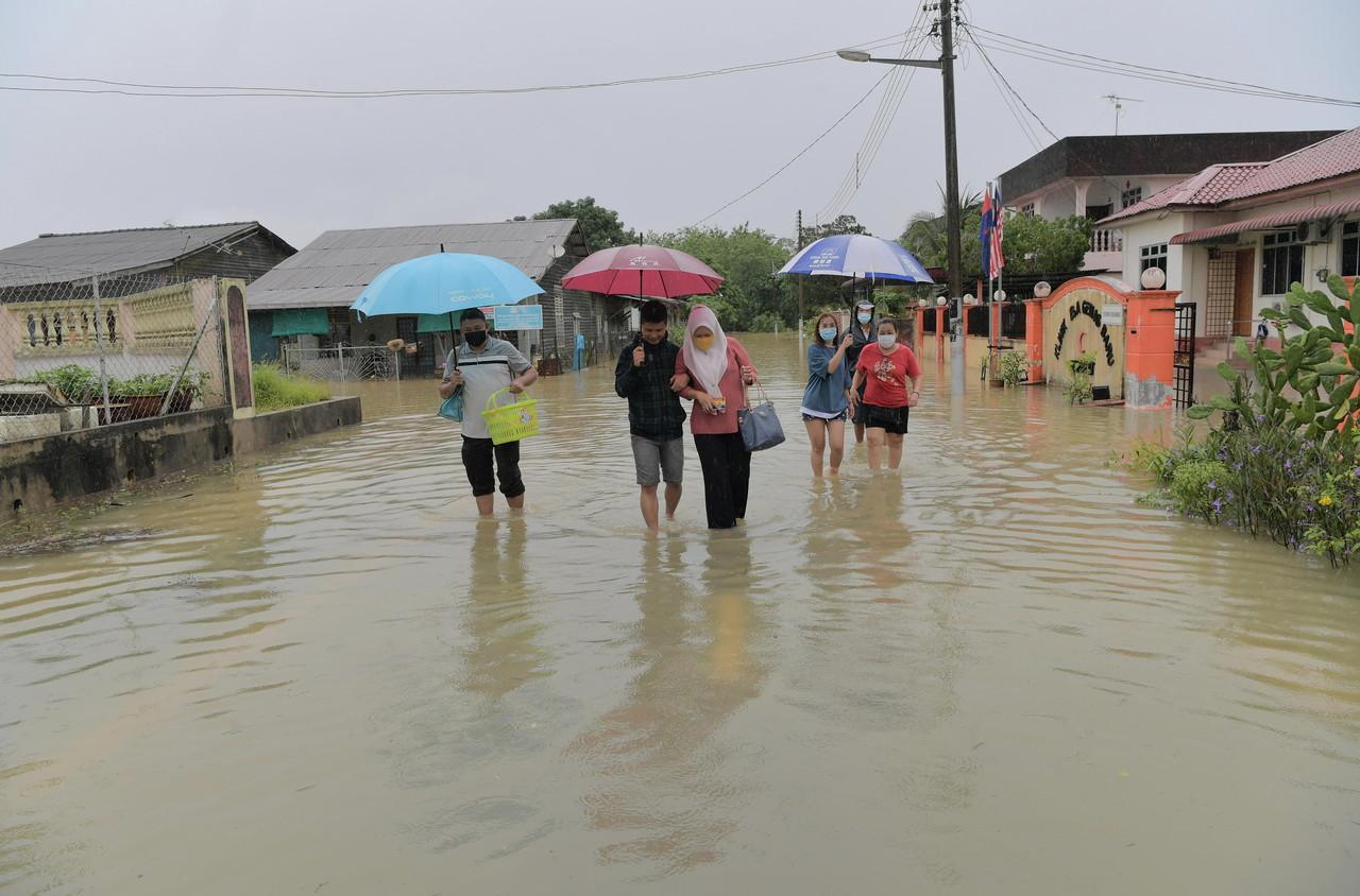 Residents in Segamat wade through flood waters as they leave their homes after heavy rain in Taman Gembira today. Photo: Bernama