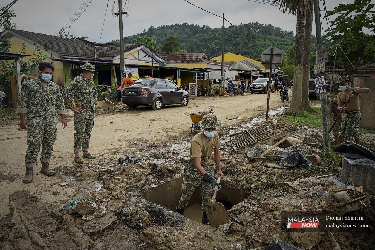 Beberapa anggota tentera dari 25 RAMD, Bentong Pahang membantu penduduk Taman Sri Nanding membersihkan longkang yang tersumbat akibat kesan banjir yang melanda Hulu Langat.