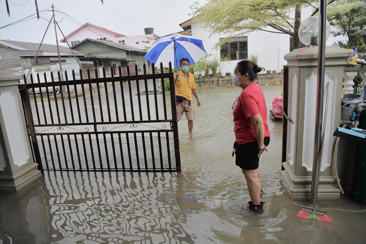 Residents of Taman Gembira in Segamat wade through ankle-deep water as the bad weather continues. Photo: Bernama