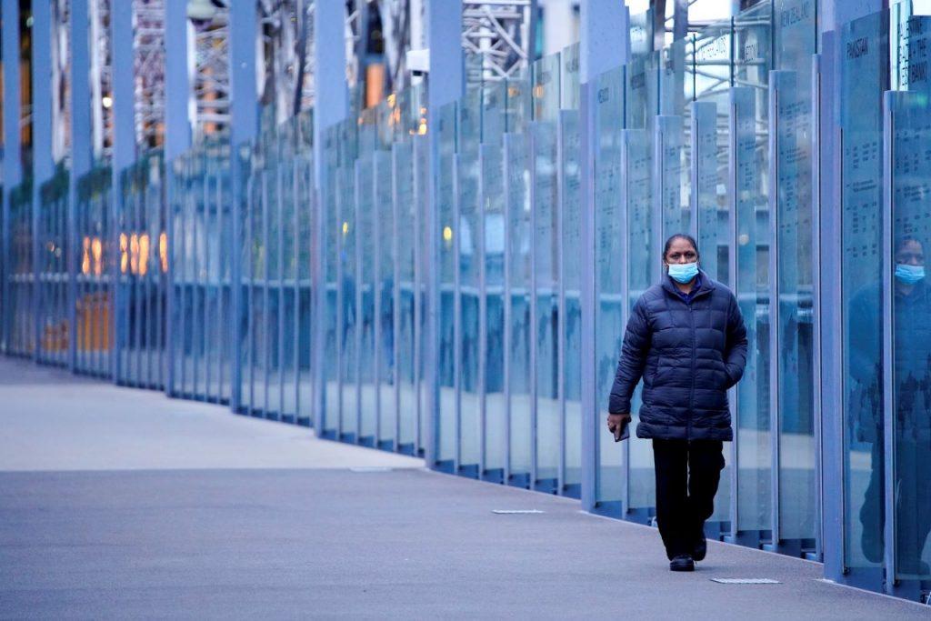 A woman wearing a protective face mask walks along a deserted city bridge during the morning commute hours in Melbourne, Australia, in this file photo dated July 16, 2021. Photo: Reuters