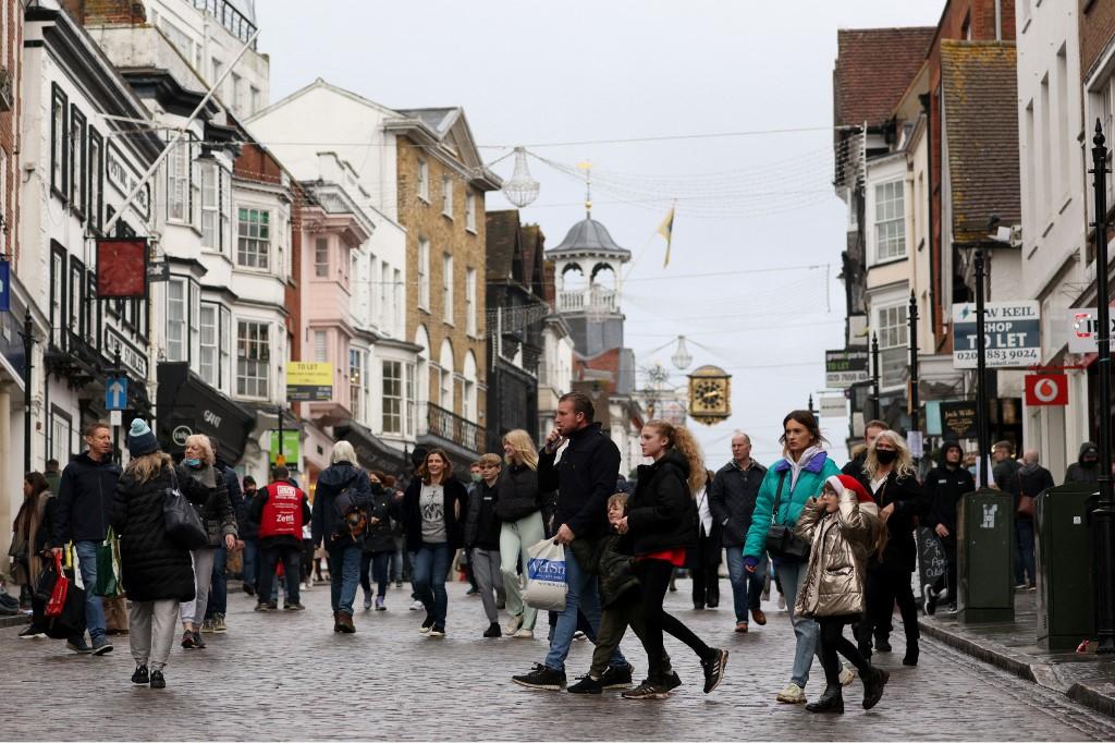 Shoppers, some wearing face coverings to combat the spread of Covid-19, pass High Street stores on Christmas Eve in Guildford, south of London. Photo: AFP